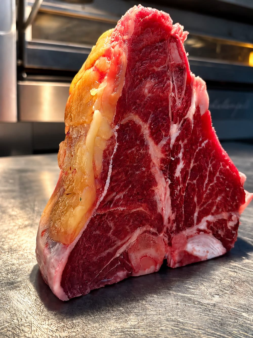Costata dry-aged con marezzatura intensa su piano in acciaio