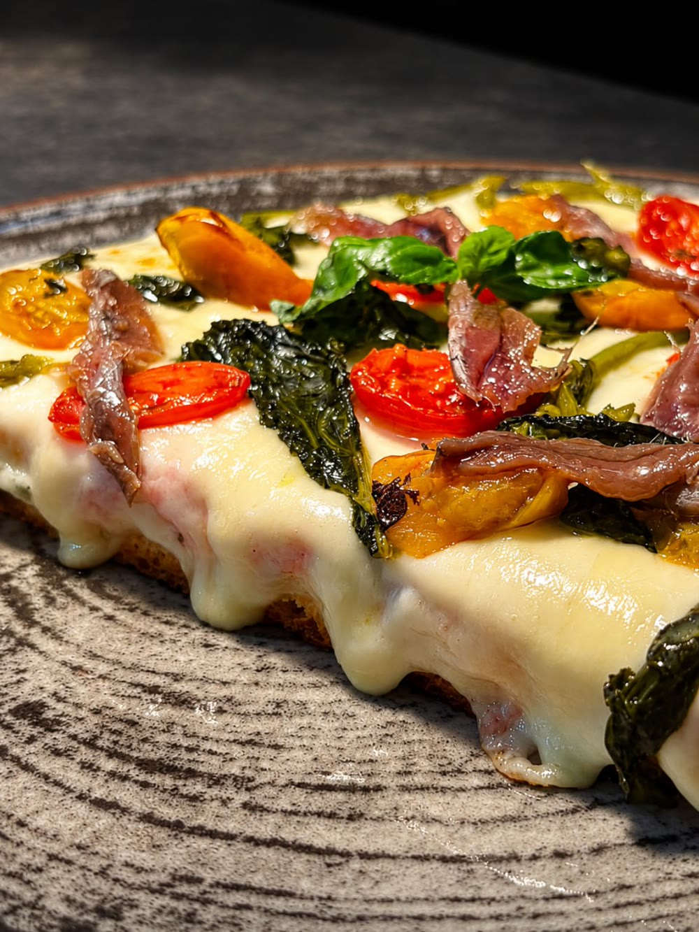 Trancio gourmet con pomodorini, acciughe ed erbe su piatto in ceramica