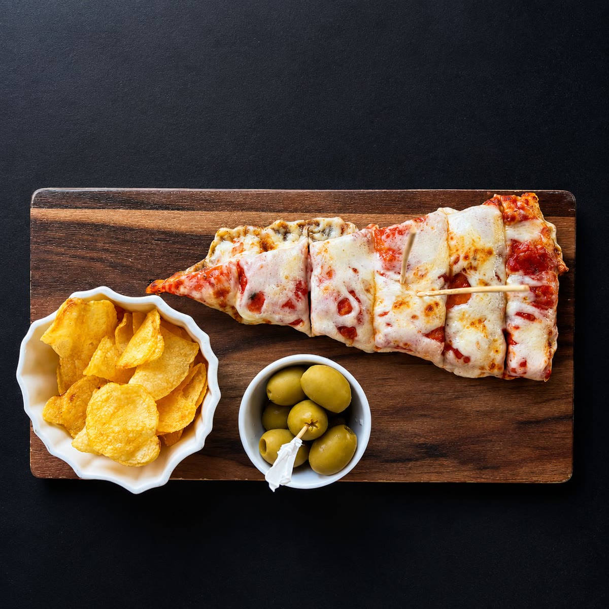 Trancio di pizza margherita su tagliere con patatine e olive